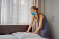 Young Female Housekeeper wearing a medical mask due to coronavirus quarantine COVID 19 Changing Bedding In Hotel Room Royalty Free Stock Photo