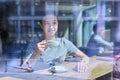 Young female inside cafe with cup of coffee, view through a glass window