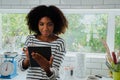 Young female in the kitchen browsing tablet for recipe, copy space