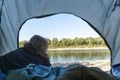 Young female lies in the tent and looks at the beautiful river out from the open window.