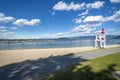 A young female lifeguard stands on duty at her lifeguard station along the sandy city beach at Sandpoint, Idaho