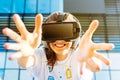 Young female with long hair wearing virtual reality glasses and big headphones outdoor. Wide smile and open hands toward screen.