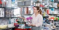 Young female looking ware for wine bottle in the tableware store