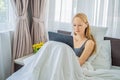 Young female lying in bed in morning, holding tablet computer, watching videos, reading news, looking relaxed and calm