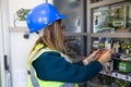 Young female maintenance engineer testing voltage with digital multimeter