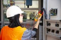 Young female maintenance engineer testing voltage with digital multimeter