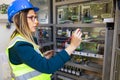 Young female maintenance engineer testing voltage with digital multimeter