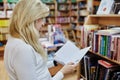 Young female making order on bookshelves in college, teacher picking literature for education