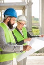 Young male and female architects or business partners looking at floor plans on a construction site Royalty Free Stock Photo
