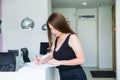 Young female manager standing at reception desk in office hall and plans working schedule, writes in notebook, makes notes of Royalty Free Stock Photo