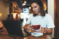 Young female manager using laptop in cafe, girl freelancer looking on monitor and drink hot coffee, businesswoman working Royalty Free Stock Photo