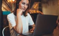 Young female manager using laptop in cafe interior, hipster girl freelancer looking on computer monitor, businesswoman working Royalty Free Stock Photo