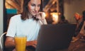 Young female manager using laptop in cafe interior, hipster girl freelancer looking on computer monitor, businesswoman working Royalty Free Stock Photo