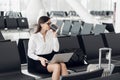 Young female managing director is reading e-mail on laptop and listening music, while is waiting her fly in Royalty Free Stock Photo