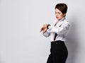 Young female managing director in white shirt and pants with suspenders is checking her watch over white with copy space Royalty Free Stock Photo