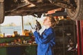 Young female mechanic works under the car