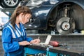 Young Female Mechanic Making Notes In Garage