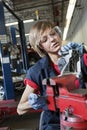 Young female mechanic in protective workwear working on machinery part in automobile repair shop Royalty Free Stock Photo