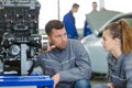 Young female mechanics changing tire from suspended car at garage Royalty Free Stock Photo