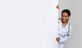 Young female medical intern looking out of behing white advertising board Royalty Free Stock Photo