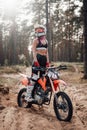 Young female motocross racer in safety helmet riding on her motorcycle in off road adventure