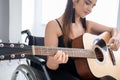Young female musician in wheelchair playing guitar Royalty Free Stock Photo