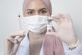 Young female muslim doctor holding a syringe with covid-19 vaccine bottle for injection, covid-19 vaccination and health care Royalty Free Stock Photo