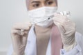 Young female muslim doctor holding a syringe with covid-19 vaccine bottle for injection, covid-19 vaccination and health care Royalty Free Stock Photo