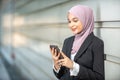 Young Female Muslim Entrepreneur looking at her smartphone