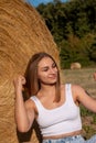 Young female near a pile of hay bales, in a peaceful rural setting