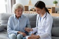 Young female nurse measure blood pressure check old grandma patient Royalty Free Stock Photo