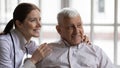 Young nurse hugs old man patient smiling look at distance