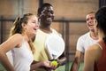 Young female paddle tennis player talking to friends on indoor court