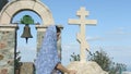 Young female parishioner saying prayers outside church, touching stone cross
