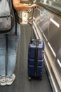 Young female passenger holding hand-carry suitcase on escalator at airport Royalty Free Stock Photo