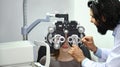 Young female patient checking eye vision with phoropter eyesight measurement testing machine in clinic Royalty Free Stock Photo