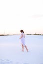 Young female person wearing white dress walking barefoot on sand Royalty Free Stock Photo