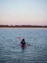 Young female person woman girl in red yellow kayak paddling into sunset clear blue ocean water Mallorca Spain Royalty Free Stock Photo