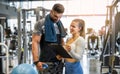 Young female personal trainer showing exercise progress to male client in gym. Royalty Free Stock Photo