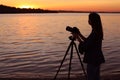 Young female photographer adjusting professional camera on tripod Royalty Free Stock Photo