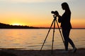 Young female photographer adjusting professional camera on tripod Royalty Free Stock Photo