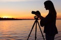 Young female photographer adjusting professional camera on tripod Royalty Free Stock Photo