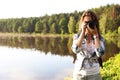 Young female photographer with camera on shore of lake Royalty Free Stock Photo