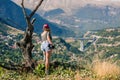 Young female photographer with professional camera near big old tree opposite greek village. A girl with camera opposite the villa Royalty Free Stock Photo