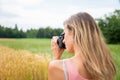 Young female photographer taking a photo of fields in nature Royalty Free Stock Photo