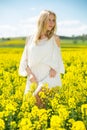 Young female posing in yellow oilseed rape field wearing in white dress Royalty Free Stock Photo