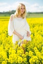 Young female posing in yellow oilseed rape field wearing in white dress Royalty Free Stock Photo