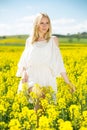 Young female posing in yellow oilseed rape field wearing in white dress Royalty Free Stock Photo