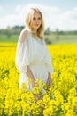 Young female posing in yellow oilseed rape field wearing in white dress Royalty Free Stock Photo