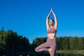 Young female practicing yoga against the sky on a sunrise. Pretty slim woman performs an exercise. Healthcare, meditaion